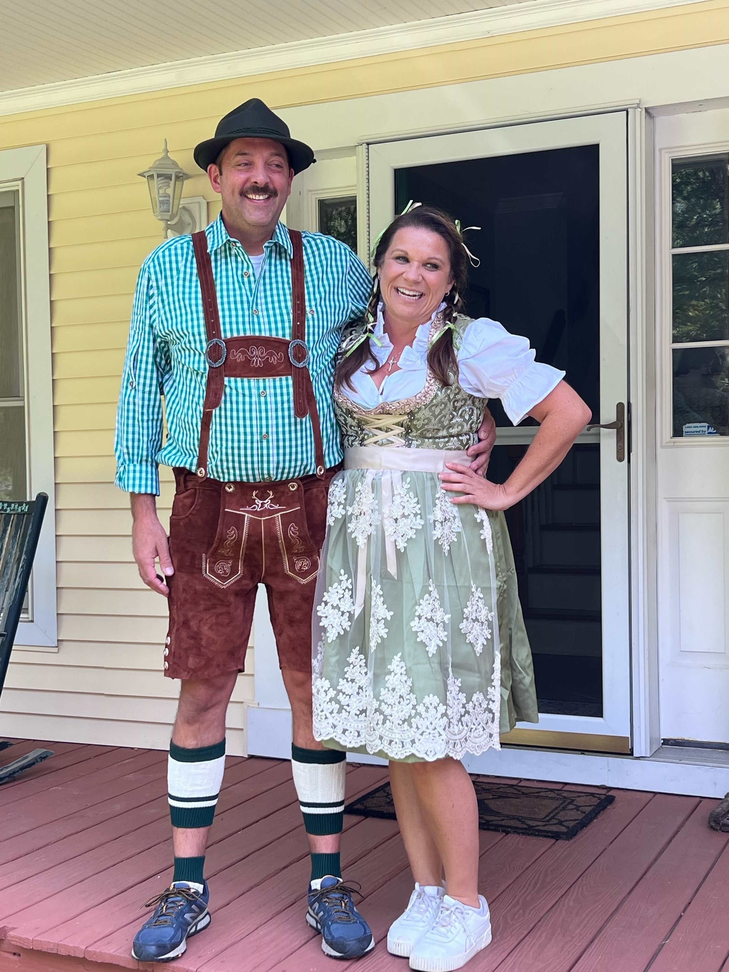 Two people in traditional German clothing standing on a porch.