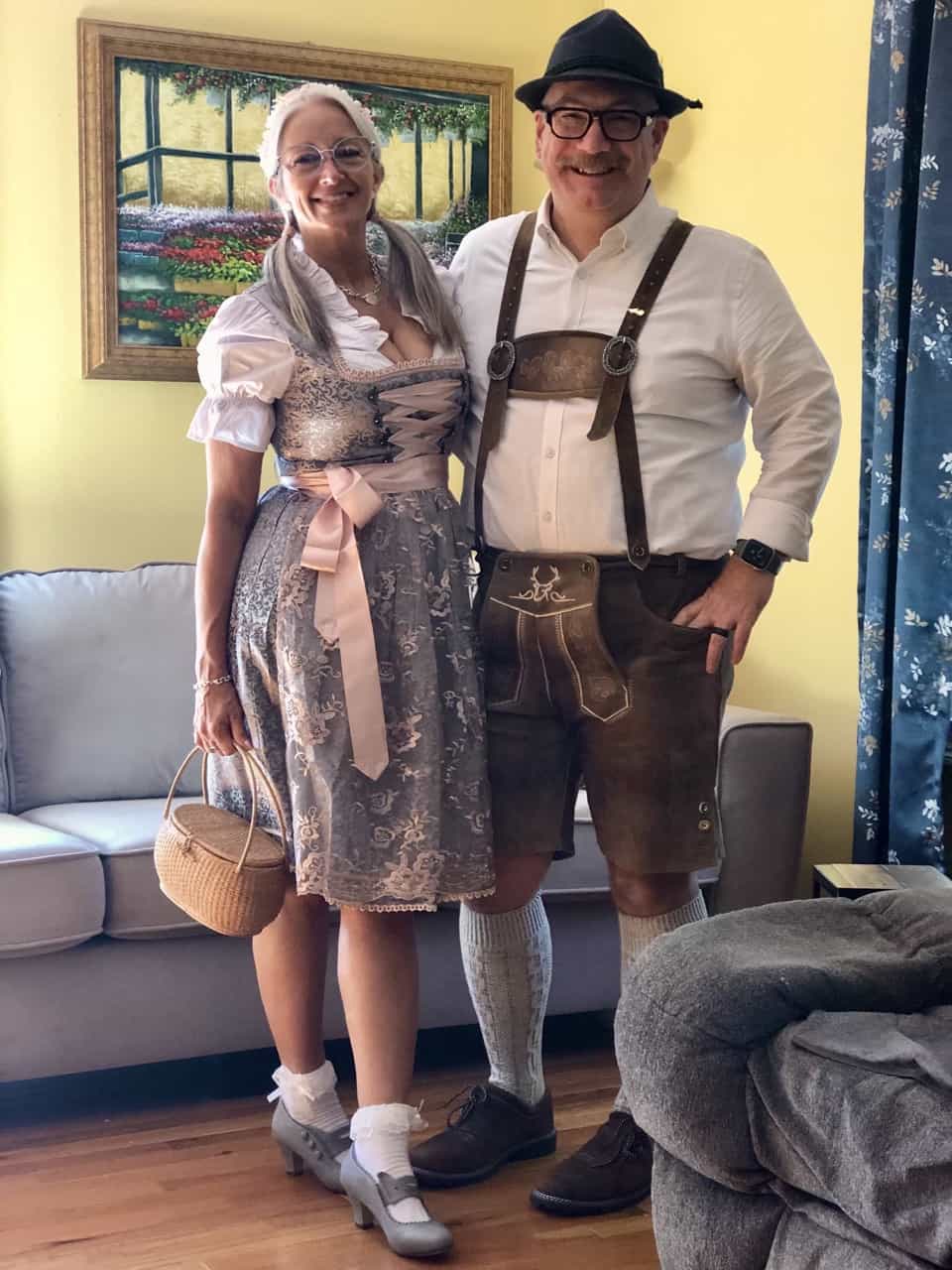 Two people in traditional German attire standing in a living room.